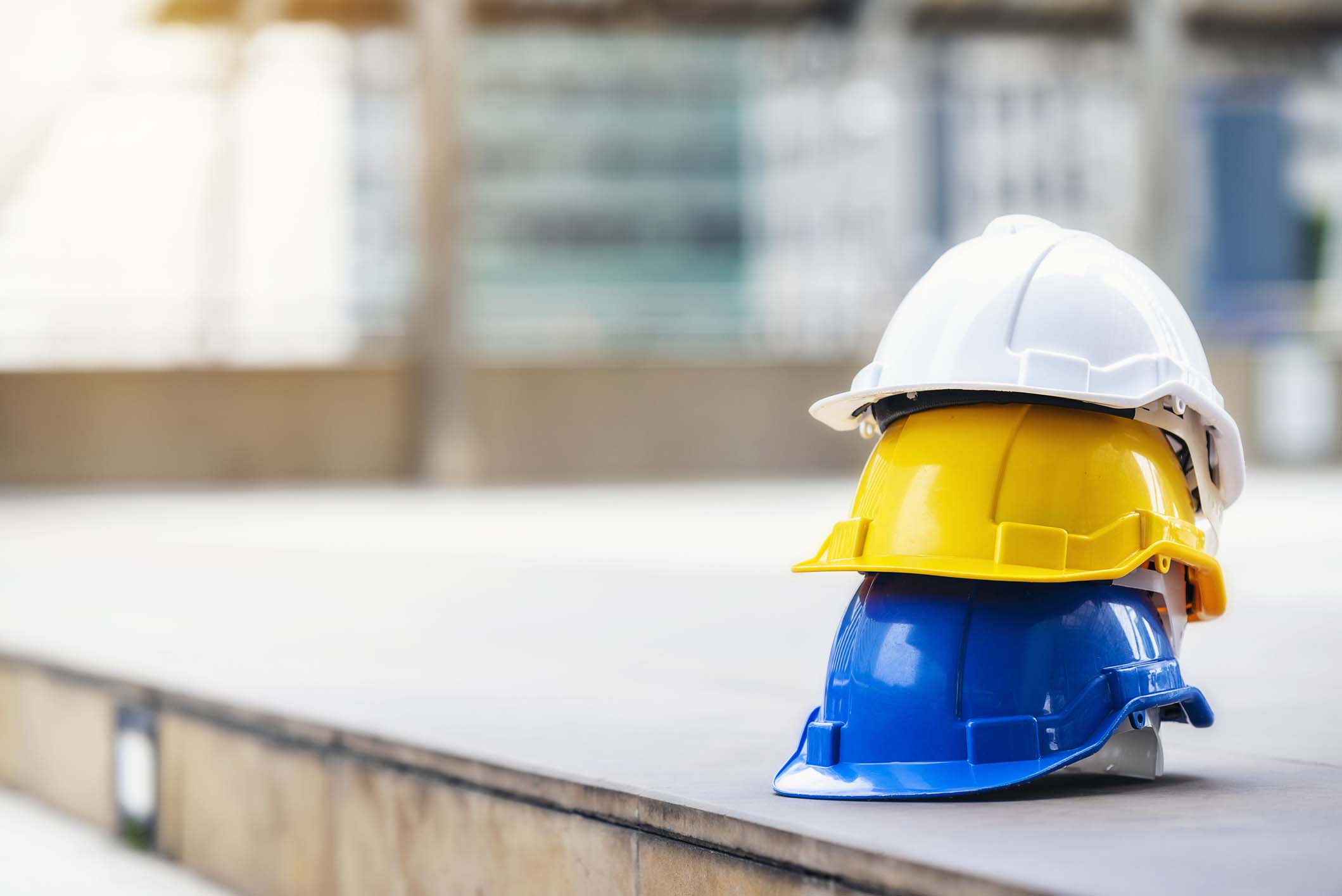 white, yellow and blue hard safety helmet hat for safety project of workman as engineer or worker, on concrete floor on city.;